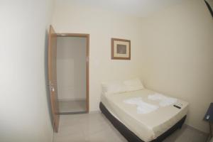 Dormitorio pequeño con cama y espejo en Hotel hawaii, en Campos dos Goytacazes