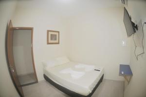 um pequeno quarto com uma cama e uma televisão em Hotel hawaii em Campos dos Goytacazes