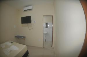 a room with a bed and a bathroom with a television at Hotel hawaii in Campos dos Goytacazes