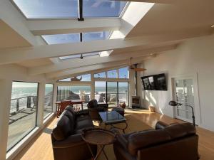 sala de estar con sofá, mesa y ventanas en Stunning Oceanfront Escape, en Bodega Bay
