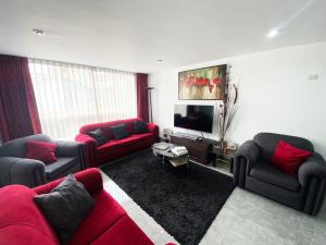 sala de estar con sofás rojos y TV de pantalla plana en Ayli Apart Hotel, en Arequipa
