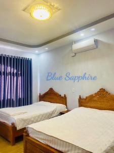 2 Betten in einem Zimmer mit blauem Saphir-Schild an der Wand in der Unterkunft Nhà Nghỉ Blue Sapphire - hotel in Xuyên Mộc