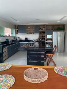 a large kitchen with a table and a refrigerator at Casa de luxo em condomínio in Arraial do Cabo