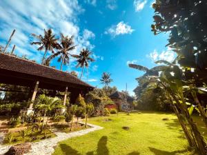 a garden in front of a house with palm trees at Apit Lawang Villas & Resto in Nusa Penida