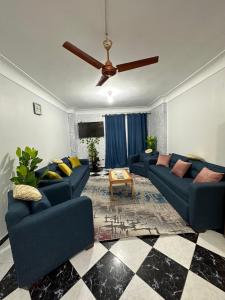 salon z niebieskimi kanapami i wentylatorem sufitowym w obiekcie Appartement à Miami - Vu sur mer w Aleksandrii