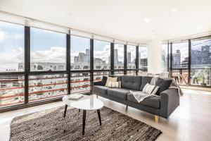 a living room with a couch and large windows at KULA Docklands in Melbourne