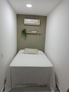 małą sypialnię z łóżkiem z białym kocem w obiekcie Flat Container Pontal do Atalaia w mieście Arraial do Cabo