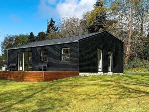 une maison noire sur une cour avec une pelouse dans l'établissement Holiday home Melby VI, à Melby