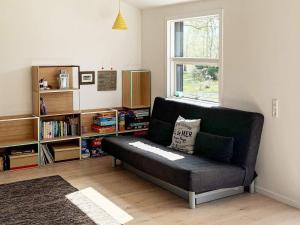 - un canapé noir dans un salon avec une étagère dans l'établissement Holiday home Melby VI, à Melby