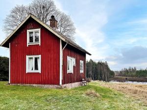 uma casa vermelha sentada em cima de um campo em Holiday home FÄRGELANDA V em Färgelanda