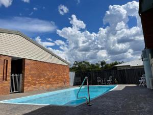 a swimming pool in front of a building with a blue sky at Abajaz Motel-All Rooms Updated-May 2024 in Longreach