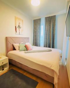 1 dormitorio con 1 cama con sábanas blancas y almohadas coloridas en Stan na dan "Apartman Purple", en Banja Luka
