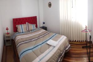 1 dormitorio con 1 cama grande y cabecero rojo en Cusco Central Aparment, en Cusco