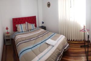 sypialnia z dużym łóżkiem z czerwonym zagłówkiem w obiekcie Cusco Central Aparment w Cuzco