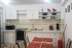 a kitchen with white cabinets and a table with a red rug at Cusco Central Aparment in Cusco