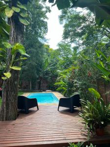 een houten terras met stoelen naast een zwembad bij Casa Jaguar in Puerto Iguazú
