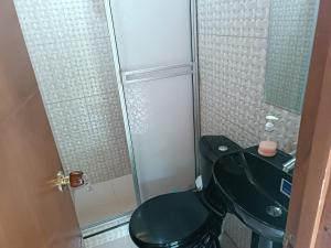 ein Bad mit einem schwarzen WC und einer Dusche in der Unterkunft Cabaña independiente en Granja Agroecologica in Anolaima