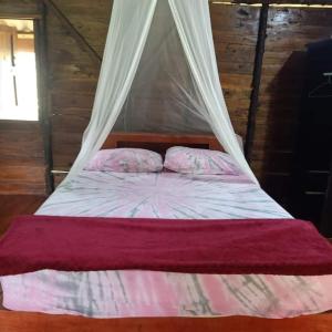 a bed with a canopy and two pillows on it at Koom Kachanaan in Ban Nong Thale