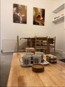 a wooden table with four coffee cups on it at Two Bedroom Flat in London in London