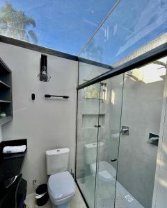 a bathroom with a toilet and a glass shower at Chalé Aconchegante - TEMOS O CHALÉ BRANCO DISPONÍVEL NESTE FINAL DE SEMANA in Camboriú