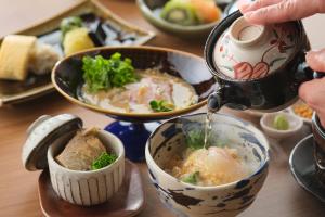 una persona vertiendo sopa en un tazón con tetera en Onomichi Hansei en Onomichi