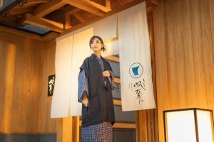 uma mulher em pé num palco em frente a uma faixa em Onomichi Hansei em Onomichi