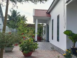 una casa blanca con plantas y una pasarela en HOMESTAY HT, en Vĩnh Long