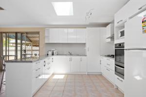 cocina blanca con armarios blancos y suelo de baldosa en Bea-Vic Home. Your home away from home., en Kalgoorlie
