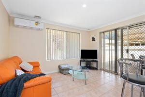 ein Wohnzimmer mit einem orangenen Sofa und einem TV in der Unterkunft Bea-Vic Home. Your home away from home. in Kalgoorlie