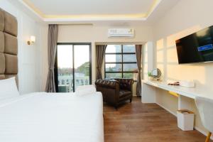 Habitación de hotel con cama, silla y escritorio. en Calinton Hotel en Udon Thani