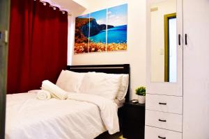 ein Schlafzimmer mit einem weißen Bett und einem roten Vorhang in der Unterkunft 1 Bedroom with balcony in Manila