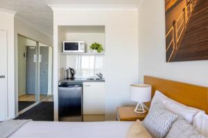 a bedroom with a bed and a kitchen with a microwave at Aligned Corporate Residences Townsville in Townsville