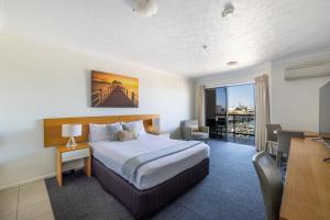 a hotel room with a bed and a desk and a table at Aligned Corporate Residences Townsville in Townsville