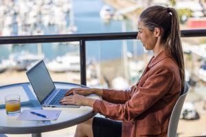 a woman sitting at a table using a laptop computer at Aligned Corporate Residences Townsville in Townsville
