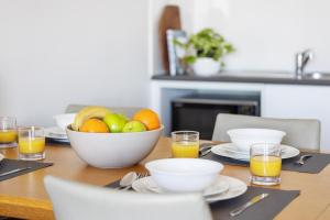 a table with a bowl of fruit and glasses of orange juice at Aligned Corporate Residences Townsville in Townsville