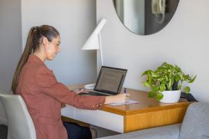 a woman sitting at a desk with a laptop computer at Aligned Corporate Residences Townsville in Townsville