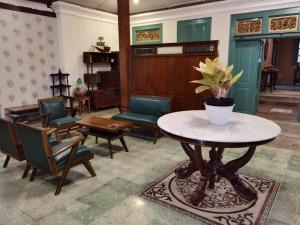 スラカルタにあるNdalem Kinasih Homestay Syariahの椅子と鉢植えのテーブルが備わる部屋