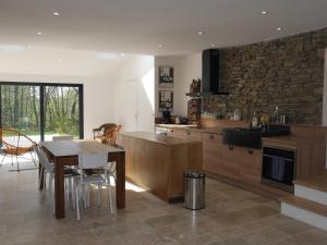a kitchen with a table and a stone wall at Maison contemporaine au calme près de la plage, WiFi inclus - FR-1-418-198 in Locmaria