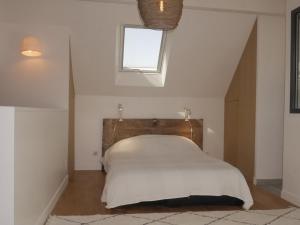 a bedroom with a bed with white sheets and a window at Maison contemporaine au calme près de la plage, WiFi inclus - FR-1-418-198 in Locmaria