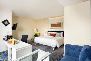 a bedroom with a white bed and a blue chair at Jambuluwuk Malioboro Hotel Yogyakarta in Yogyakarta