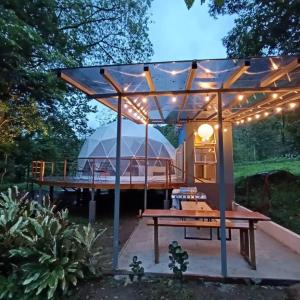 a gazebo with a picnic table and a tent at Bitzu Dome-Bijagua Riverside Glamping in Bijagua
