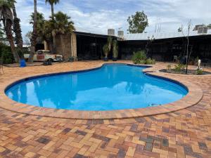 a large swimming pool in a brick patio at Albert Park Motor Inn-KING BEDS-POOL-SHADED PARKING in Longreach