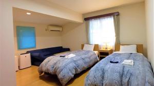 um quarto com 2 camas e um sofá azul em Le Port Awashima em Mitoyo