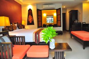 a hotel room with a bed and a table and chairs at Navatara Phuket Resort - SHA Extra Plus in Rawai Beach