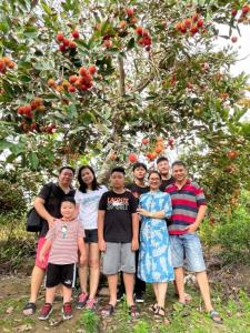 un gruppo di persone che si trovano di fronte a un albero di mele di Rooster Mekong Garden & Villas a Ben Tre