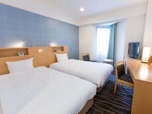 a hotel room with two beds and a desk and a television at Shibuya Tobu Hotel in Tokyo