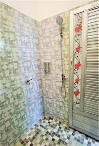 a bathroom with a shower with red flowers on the wall at Ndalem Kinasih Homestay Syariah in Solo