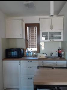 a kitchen with white cabinets and a sink and a microwave at Boletov Raj in Čurug