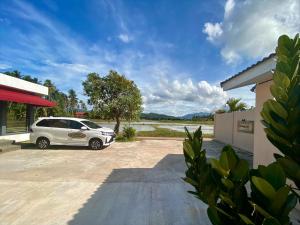 une voiture blanche garée sur un parking dans l'établissement The Paddy Field - Private Pool Villas, à Pantai Cenang