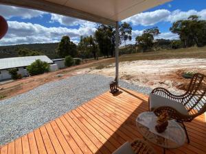 eine Holzterrasse mit einer Bank und einem Regenschirm in der Unterkunft Serenity at Valley View in Chittering in Chittering